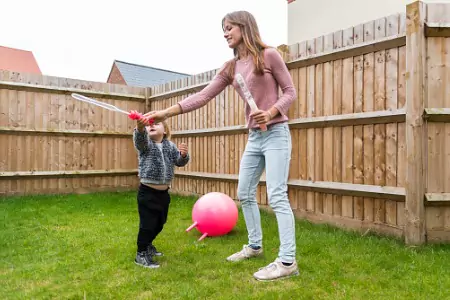 A woman makes bubbles with her toddler after installing cedar privacy Fencing in Shorewood IL